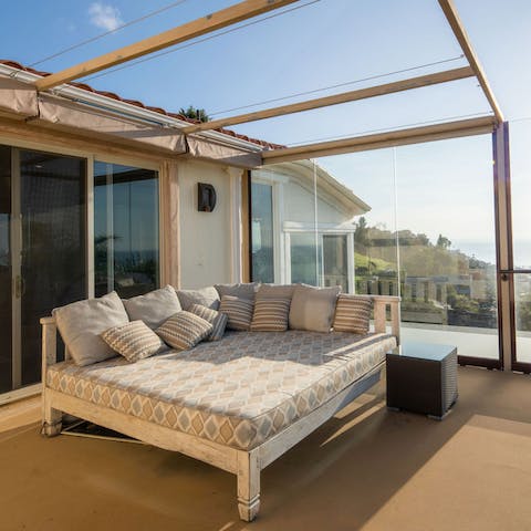 Recline on the day bed as the sun sets over the ocean