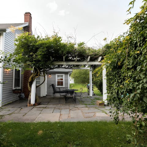 Enjoy a glass of wine on the patio under the wisteria-clad pergola