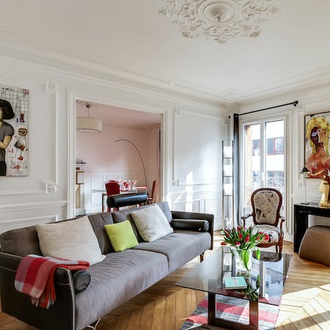 Unwind on the comfy, grey sofa after a busy day exploring Paris