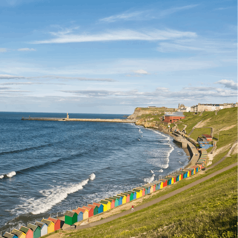 Stroll along Whitby's West Cliff Beach, lined with iconic beach huts