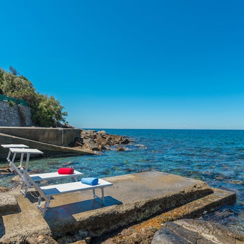 Laze on loungers in the sun on the promontory before bathing in the turquoise Tuscan waters