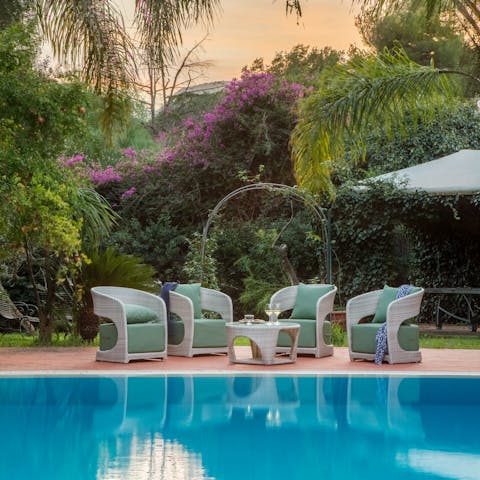 Sit by the pool, surrounded by the stunning palms and vibrant vegetation that surrounds the garden