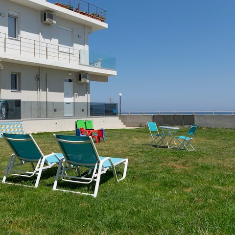 Laze on sun loungers in the large communal garden by the sea