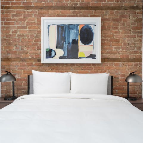 Get some rest in the stylish master bedroom with its exposed stone walls and modern artwork
