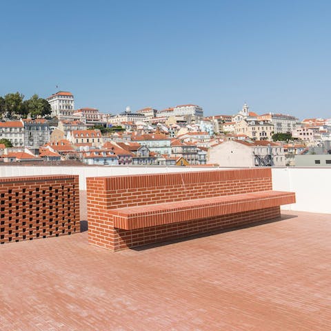 Watch Lisbon take on a golden glow at sunset on the shared roof terrace