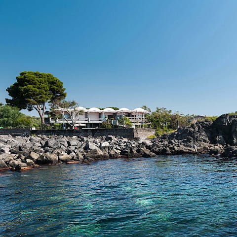 Admire the striking architecture of your modern villa from a boat on the water