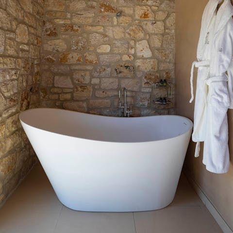 Sink back into steamy water in the elegant freestanding bathtub