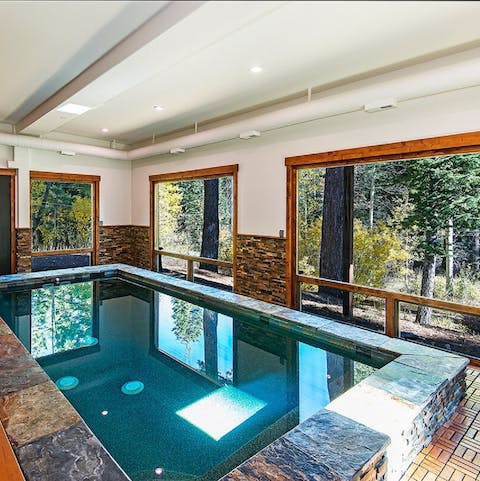 An indoor pool with a view into the forest