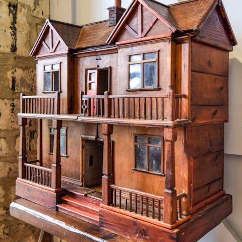 Admire the intricately carved wooden dollhouse