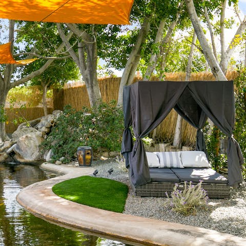 Treat yourself to a siesta on the day bed beside the serene pond