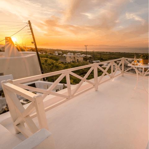 Watch the panoramic golden sunset over Santorini from your private roof terrace