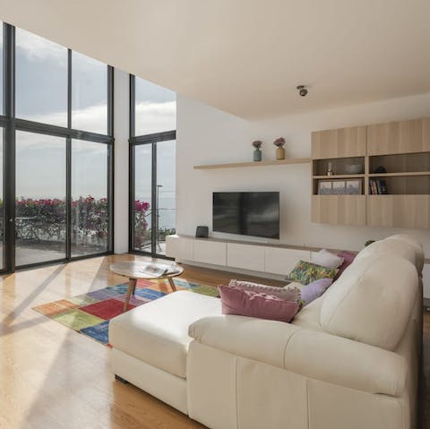 Recline in the modern living space and watch the sunset through the floor-to-ceiling windows