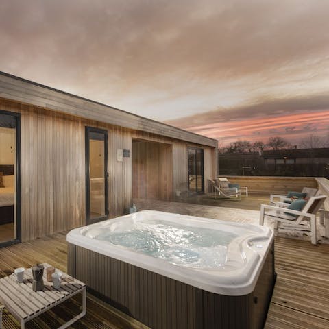 Soak in the hot tub as the sun sets over the hills