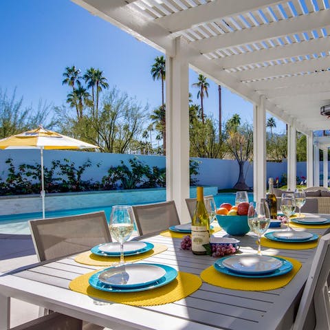 Gather around the outdoor dining table beneath the shady pergola for a barbecue feast