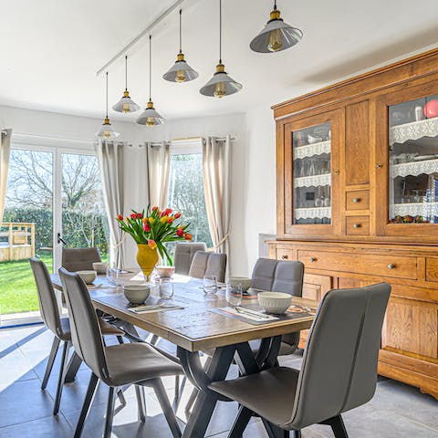 Gather around the dining table for a hearty family dinner beneath the warm-toned light fixtures