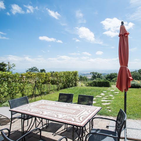 Sip Italian wine at the alfresco dining area overlooking scenic Tuscan country views