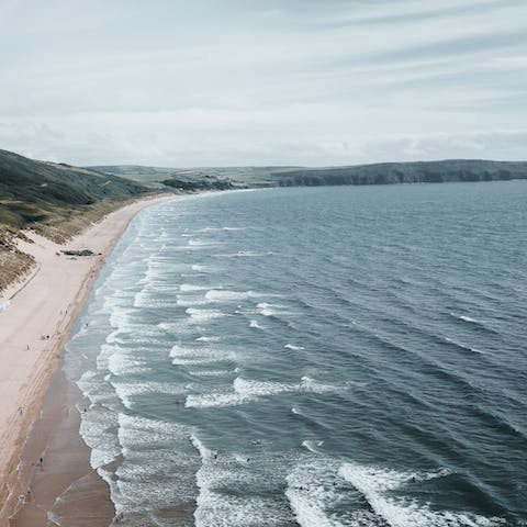 Surf the waves and sink your toes in the sands of Woolacombe Beach, a 5 mile drive away