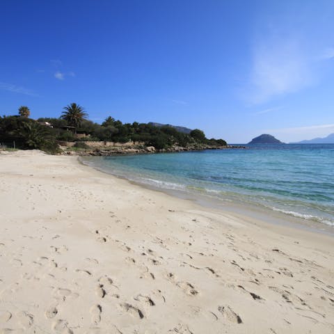Sink your feet into the sand of Baia Caddinas beach, a short walk away