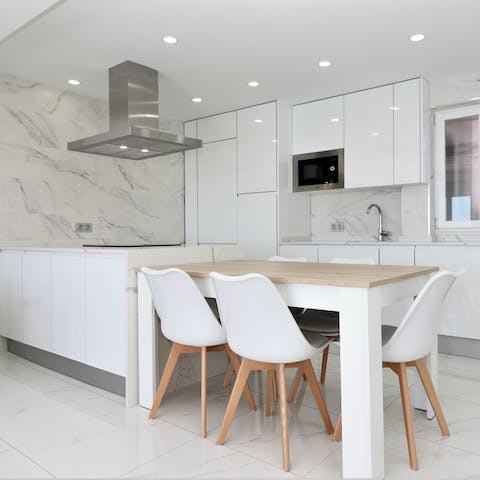 Catch up on work, eat, read, or simply socialise at this inviting table in the modern marble kitchen