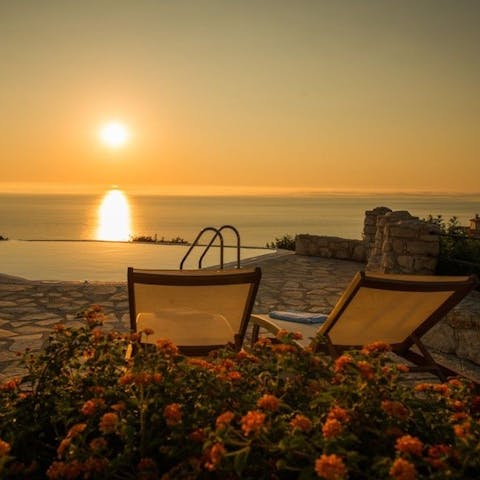 Relax on poolside loungers while you watch the sun setting over the ocean in the distance