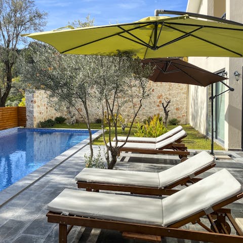 Lie back on the poolside sun loungers in the shade of the parasol after a swim