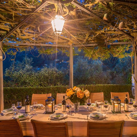 Set up for dinner by lantern light beneath the twisting grapevines