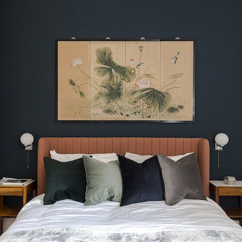 Admire the striking blue feature wall and East Asian artwork hanging above the bed