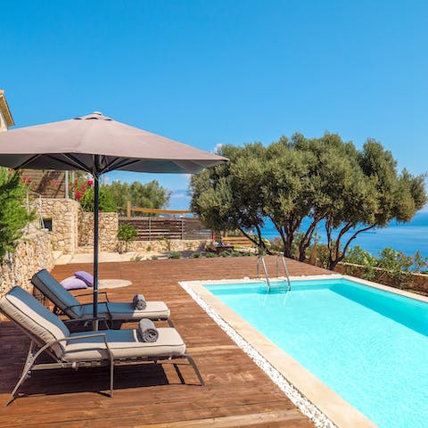 Relax on the sun loungers by the pool, with the backdrop of the iridescent Ionian sea