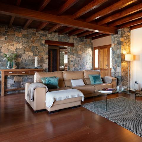Relax in the living room with its exposed volcanic stone walls
