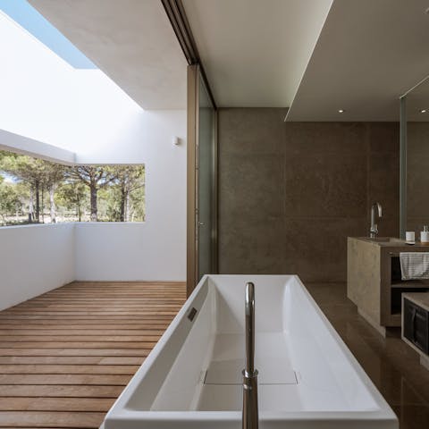 Treat yourself to a languorous soak in the boxy bathtub with the glass doors open