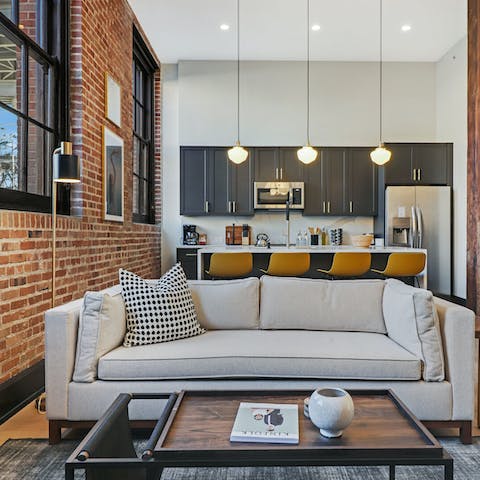 Relax in the spacious living room with high ceilings and exposed brick walls