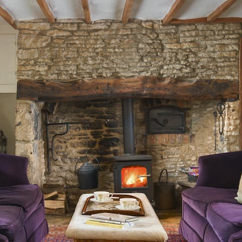 Cosy up on the velvet sofa in front of the wood-burning stove after a walk through the Cotswold countryside 
