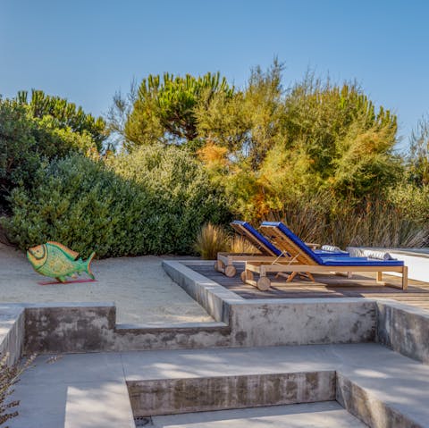 Let the kids play on the small sandy play area by the sun loungers 