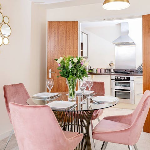 Sit down to an elegant meal at the glass dining table with its blush pink seats