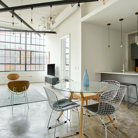 Enjoy a meal at the glass dining table in your industrial-style living space