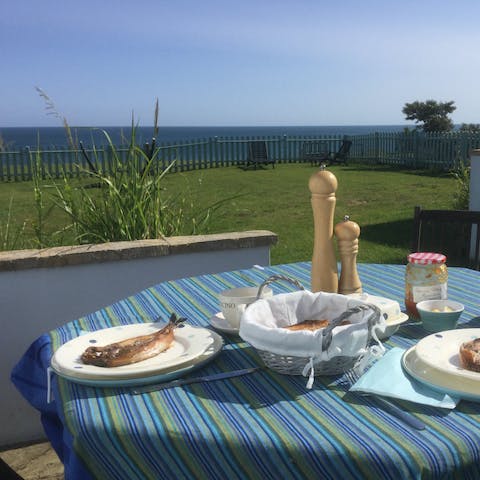 Tuck into the catch of the day in your sunny garden overlooking the sea