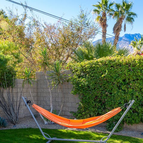 Hang out in the vibrant orange hammock in the garden surrounded by swaying palms