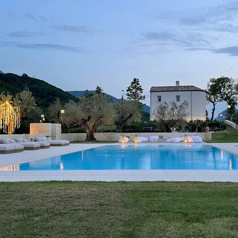 Relax beneath fairy lights on a sun lounger by the swimming pool