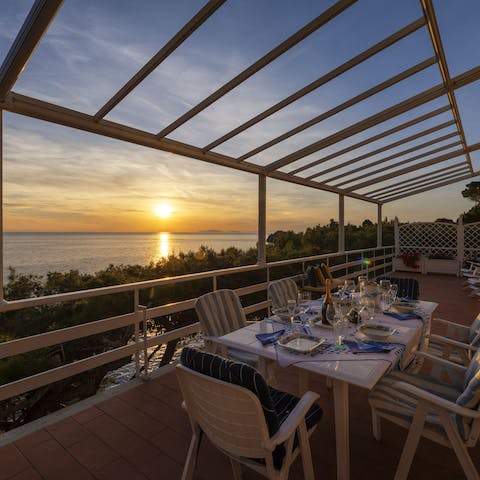 Watch the sunset from the dining terrace hanging out over the sea