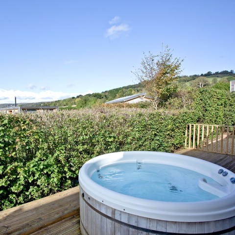 Soak in the hot tub as the sun sets over the surrounding hills