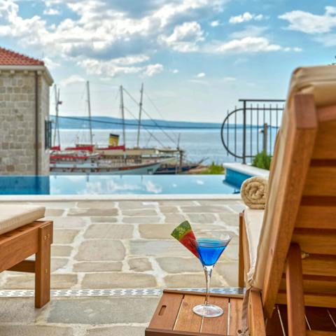 Lounge poolside with a view of boats docking at sea