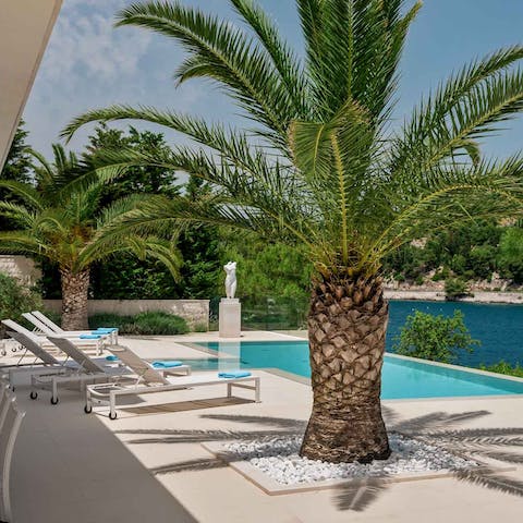 Laze by the infinity pool surrounded by palm trees before taking a dip