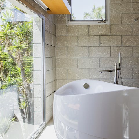 Soak in the bathtub as you look out to lush palms