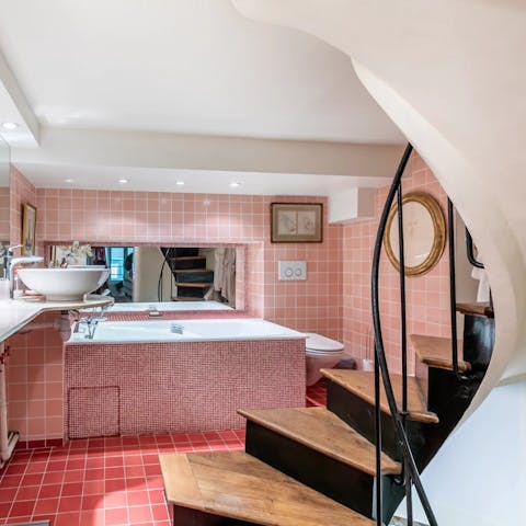 Descend a spiral staircase and unwind in the pink-tiled bathroom