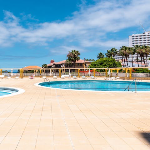 Take a relaxing dip in the communal pool with sea views in the distance 