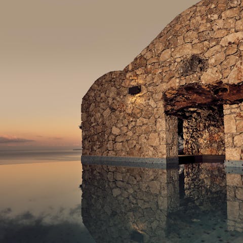 Glide through the glistening waters of your stone grotto at sunset