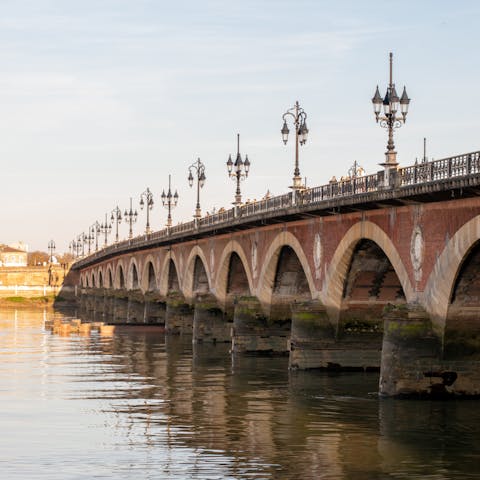 Stroll along the Pont de Pierre as the sun sets over the city