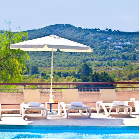 Lounge around the pool with a hillside backdrop