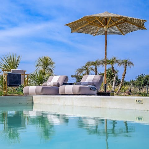 Enjoy a refreshing dip in the outdoor pool before resting on a poolside lounger