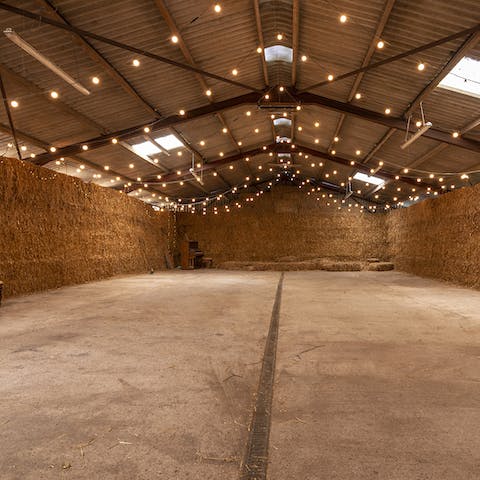Host huge events in the fairylit barn soundproofed by haybales